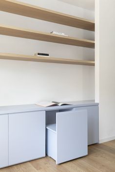 an empty room with open shelves and books on the top shelf, in front of a bookcase