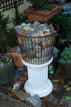 a birdcage filled with lots of rocks sitting on top of a stone floor