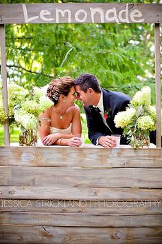 a bride and groom sitting in front of a lemonade sign