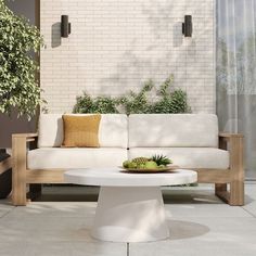 a white couch sitting on top of a wooden table next to a potted plant