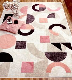 an area rug with various shapes and colors on the floor next to a vase filled with flowers