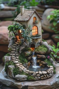 a small house with a waterfall in front of it and some plants on the rocks