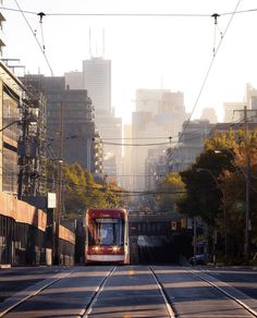 a red train traveling down tracks next to tall buildings and power lines in the city