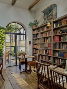 a room with many bookshelves and wooden chairs in front of an arched window