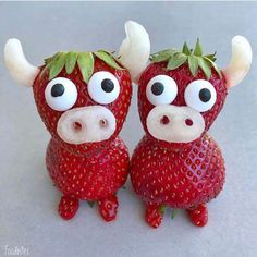 two strawberries with googly eyes and horns on their heads are sitting next to each other