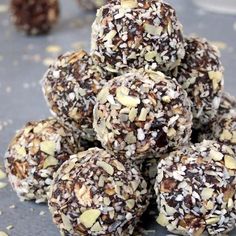 a pile of chocolate covered balls sitting on top of a gray surface next to a bowl