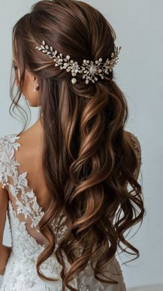 a woman with long hair wearing a bridal headpiece in her hand and looking back at the camera