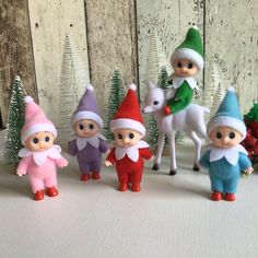 small elf figurines lined up in front of christmas trees