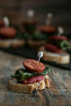 small sandwiches with toothpicks on them sitting on a wooden table next to other food items