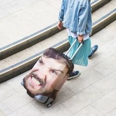 a man pulling luggage with a face on it