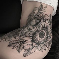 a sunflower tattoo on the side of a woman's thigh