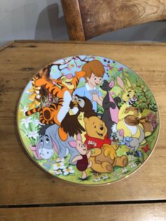 a plate with winnie the pooh and friends on it sitting on a brown surface