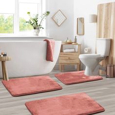 three bathroom rugs on the floor in front of a bathtub, toilet and sink