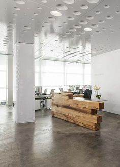 an office with white walls and wooden desks in the center, along with lots of windows