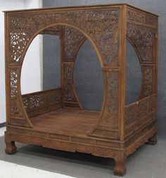 an old wooden stand with carved designs on the top and bottom, in front of a gray wall