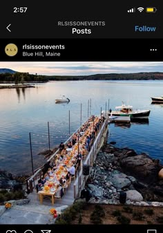 a group of people that are sitting at a table on some rocks by the water