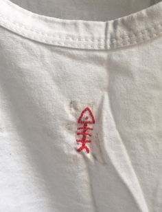 a white t - shirt with red embroidered on the chest