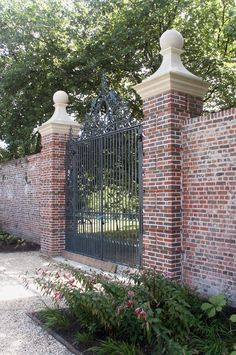 an iron gate is surrounded by brick walls