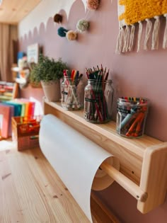 there are many craft supplies on the shelf next to the wall and in front of it is a roll of paper