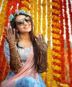 a woman sitting on the ground with her hands in front of her face and decorated with flowers