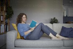 a woman sitting on a couch reading a book