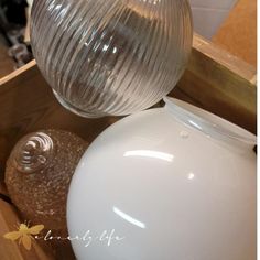 a white vase sitting on top of a wooden table next to a glass jar with a bee in it