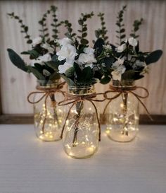 three mason jars filled with flowers and lights