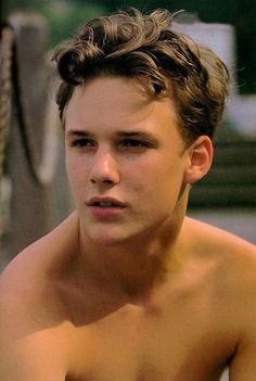 a shirtless young man sitting on top of a boat