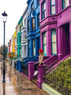 a woman with an umbrella sitting on a bench in front of some colorful building's