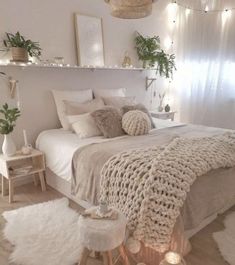 a white bedroom with lots of pillows and blankets on the bed