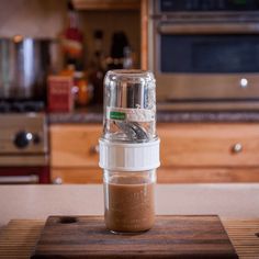 a blender filled with brown liquid on top of a wooden cutting board