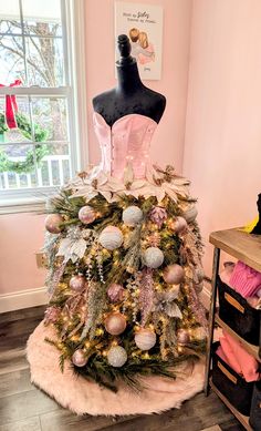 a mannequin is sitting on top of a christmas tree in a room with pink walls