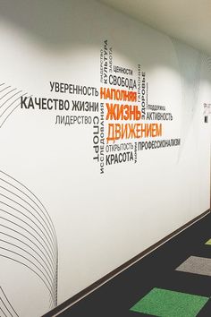 an office hallway with green and black carpeting on the floor, along with white walls that have words written in different languages