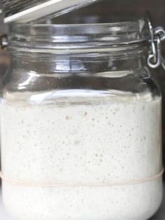 a glass jar filled with white liquid sitting on top of a counter next to a knife