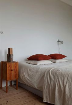 a bed with two pillows on top of it next to a night stand and nightstand