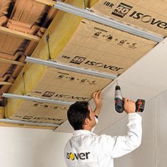 a man is working on the ceiling in his room with tools and boxes attached to it