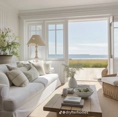 a living room filled with furniture and a large window overlooking the beach in front of it