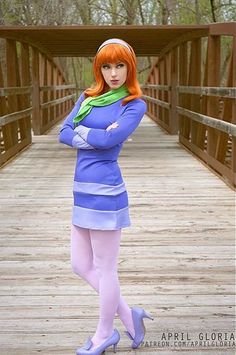 a woman with red hair and blue dress standing on a wooden bridge wearing high heels