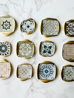 nine decorative trays with different designs on them sitting on a marble countertop top