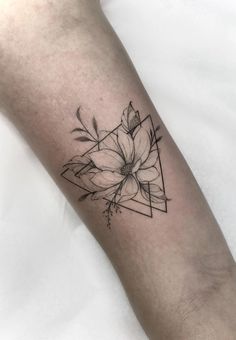 a black and white flower tattoo on the left inner arm, with geometric shapes in the background