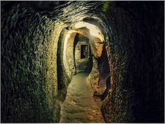 a narrow tunnel in the side of a mountain with light coming from it's windows