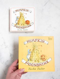 two children's books about pumpkins on a marble counter top, one is yellow and the other is orange