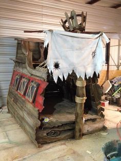 an old pirate ship made out of wood and canvas with decorations on the roof, sitting in a garage