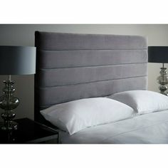 a gray headboard with white pillows and two lamps