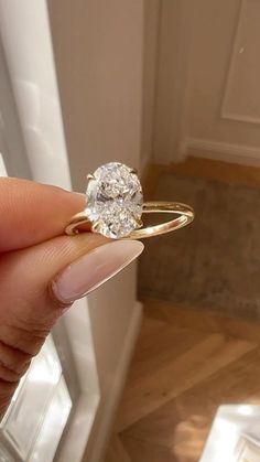 a person holding a ring with a diamond on it's finger in front of a door