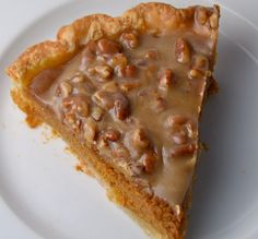 a piece of pie on a white plate with some nuts in the crust and caramel topping