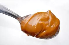 a spoon full of caramel sauce on a white surface