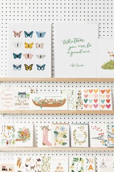 greeting cards are displayed on shelves in a room with white pegboards and polka dots