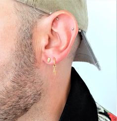 a man wearing a baseball cap and earring with a tiny gold bar on it