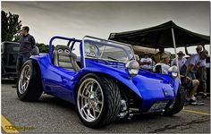 a blue sports car parked in front of a group of people